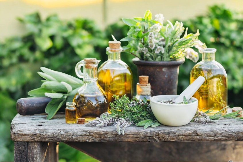 Huiles, mortier et plantes aromatiques préparés sur une table de bois